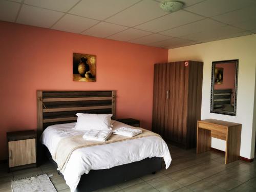 1 dormitorio con 1 cama grande y paredes de color naranja en Plot 19, en Ghanzi