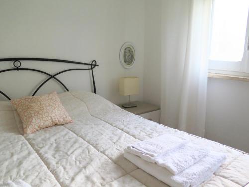 una camera da letto con un letto bianco, un cuscino e una finestra di The Bright House ad Anzio