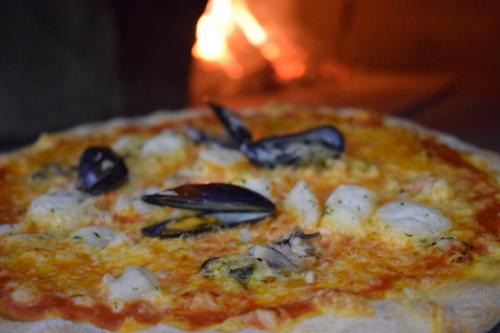 a pizza with seafood on it with a fire in the background at Hotel zum Goldenen Wagen in Maulburg
