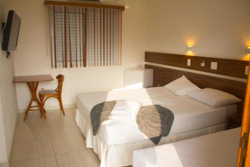 a bedroom with a bed and a table and a chair at Hotel Garrafão - Rua Principal de Boituva in Boituva