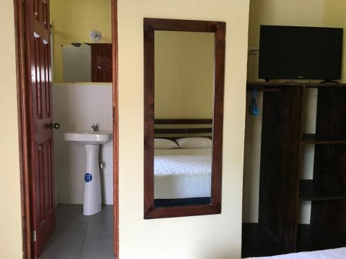 um espelho num quarto com uma cama e um lavatório em Casa Josefa Hotel em Santiago Atitlán