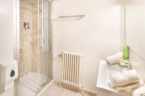 ein weißes Bad mit einer Dusche und einem Waschbecken in der Unterkunft Parkhotel in De Panne