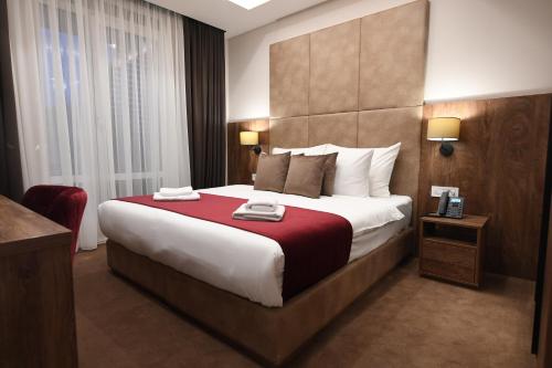 una camera da letto con un grande letto con una coperta rossa di Hammeum Hotel a Prokuplje