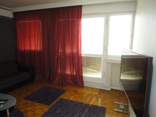 a living room with red curtains and a large window at Autokomanda in Belgrade