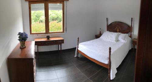um quarto com uma cama, uma mesa e uma janela em Holiday House, São Roque do Pico em Cais do Pico