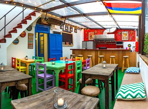 a restaurant with wooden tables and colorful chairs at Granada Hostel in Bogotá