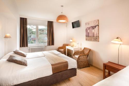 a hotel room with a bed and a desk at Parkhotel in De Panne