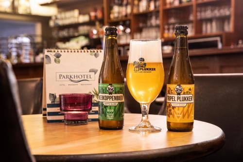 three bottles of beer sitting on a table with a glass at Parkhotel in De Panne