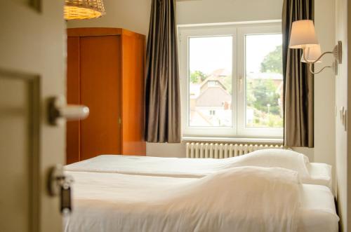 a hotel room with two beds and a window at Parkhotel in De Panne