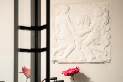 a white sculpture on a wall next to flowers at Parkhotel in De Panne