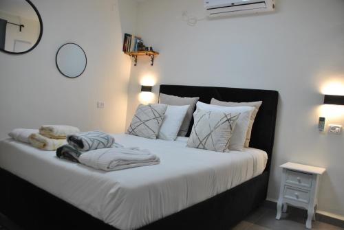 1 dormitorio con 1 cama grande con sábanas y almohadas blancas en Marvin's Place, en Arad