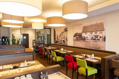 a restaurant with long tables and colorful chairs at hotel bomonti Nürnberg West in Oberasbach