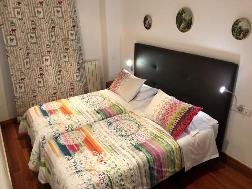 un letto con trapunta e cuscini colorati. di Apartaments Vicus 1 con vistas a la Plaza Mayor de Vic a Vic