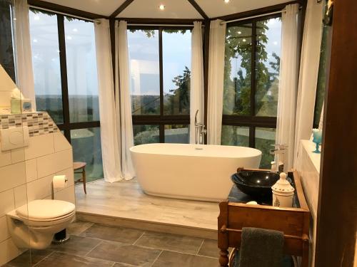a bathroom with a bath tub in a room with windows at La Coulee Verte in Saint-Aubin-de-Luigné
