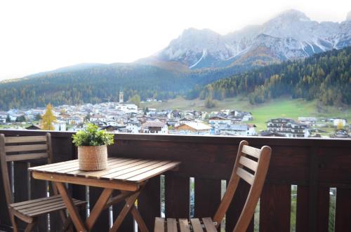 een houten tafel en stoelen op een balkon met uitzicht op de bergen bij Appartamenti Ladina in Padola