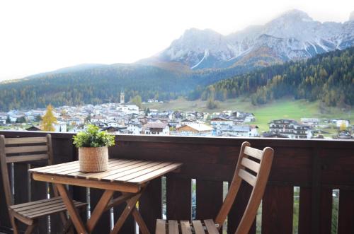 una mesa de madera y sillas en un balcón con montañas en Appartamenti Ladina, en Padola