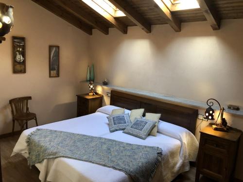 a bedroom with a large white bed with two pillows at Casa Rural El Castaño in Navalguijo