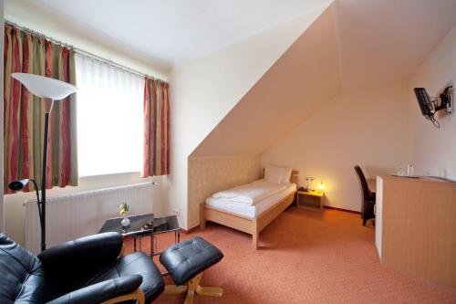 ein Wohnzimmer mit einem Sofa und einem Bett in der Unterkunft City-Hotel in Friesoythe