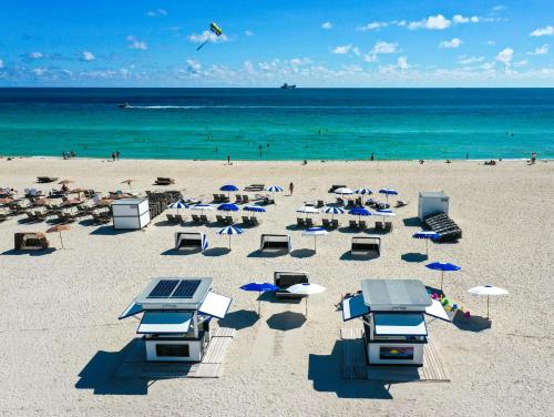 a beach with chairs and umbrellas and the ocean at The Sagamore Hotel South Beach in Miami Beach