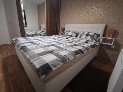 ein Schlafzimmer mit einem großen Bett mit einer karierten Decke in der Unterkunft CITY in Banja Luka
