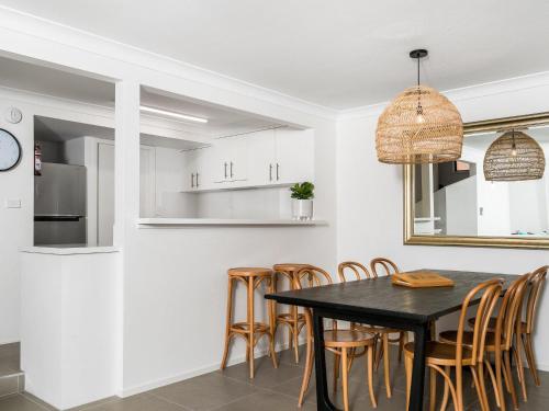 a kitchen and dining room with a black table and chairs at Calinda Sol 10 in Byron Bay