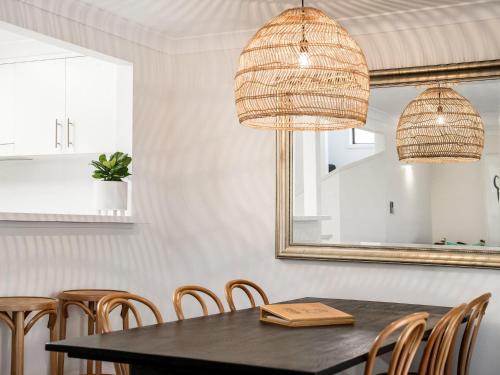 a dining room with a table and chairs and a mirror at Calinda Sol 10 in Byron Bay
