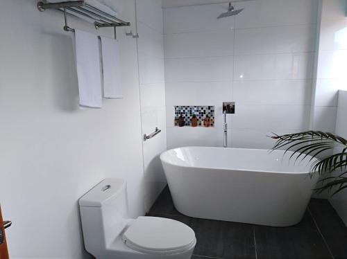 a white bathroom with a tub and a toilet at Cotinga Hotel Spa in Pereira