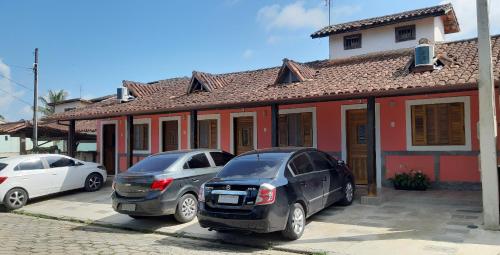 dos autos estacionados en un estacionamiento frente a una casa en Patricio's Chalés Ilhabela, en Ilhabela