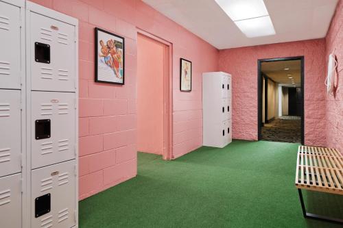 a locker room with pink walls and green carpet at Glendale Express Hotel Los Angeles in Glendale