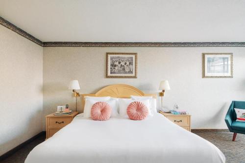 a bedroom with a large white bed with pink pillows at Glendale Express Hotel Los Angeles in Glendale