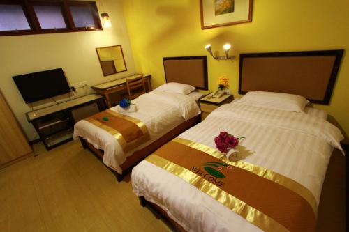 Habitación de hotel con 2 camas y TV de pantalla plana. en SIX VILLA INN, en Dungun