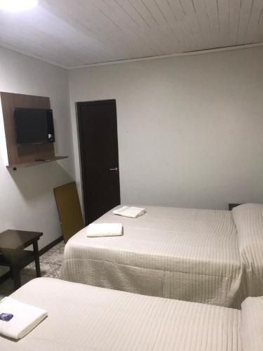 a room with two beds and a flat screen tv at Hotel Mola in Puerto Iguazú