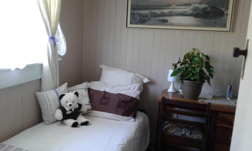 a teddy bear sitting on a bed with pillows at Share our home farm stay in Ruawaro