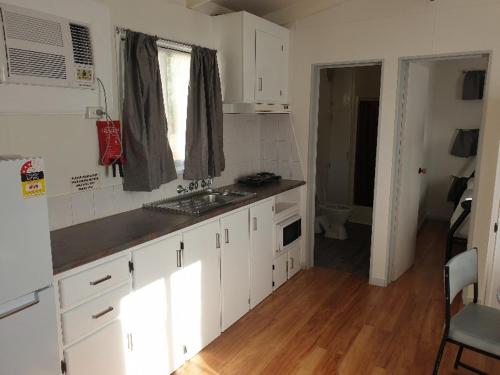 a kitchen with white cabinets and a wooden floor at Big4 Acclaim Prospector Holiday Park in Kalgoorlie