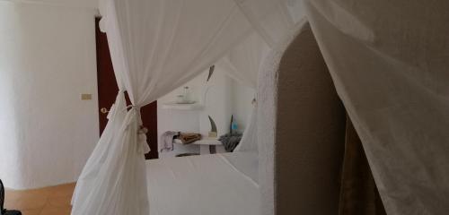 a bedroom with a bed with white curtains at AL FARO Cosmio Hotel Palawan in Busuanga