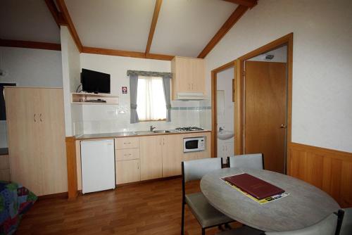 uma pequena cozinha com uma mesa e uma sala de jantar em Big4 Acclaim Prospector Holiday Park em Kalgoorlie