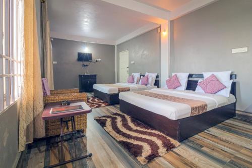 Habitación de hotel con 2 camas y mesa en 7 Sisters Falls View Inn, en Cherrapunji