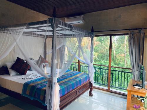 a bedroom with a canopy bed and a balcony at Sari House Ubud in Ubud