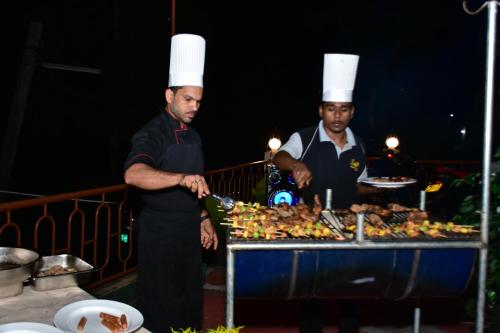 two men in chefs hats standing next to a buffet of food at HOTEL LAKEFIELD "Excellence" in Kandy