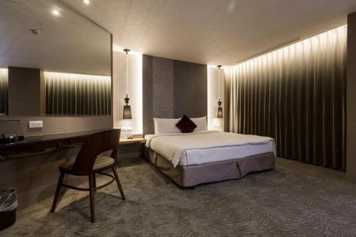 a bedroom with a bed and a desk and a mirror at Green Hotel in Magong