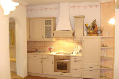 La cuisine est équipée de placards blancs et d'un four avec plaques de cuisson. dans l'établissement Gästehaus Moser, à Ramingstein