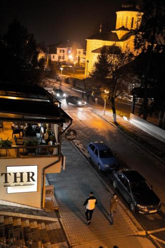 a man walking down a city street at night at Hotel THR Center in Curtea de Argeş