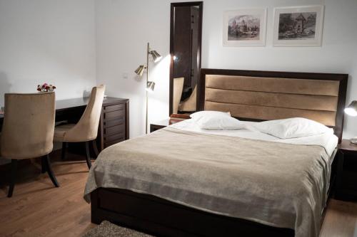a bedroom with a bed and a desk and a chair at Hotel THR Center in Curtea de Argeş