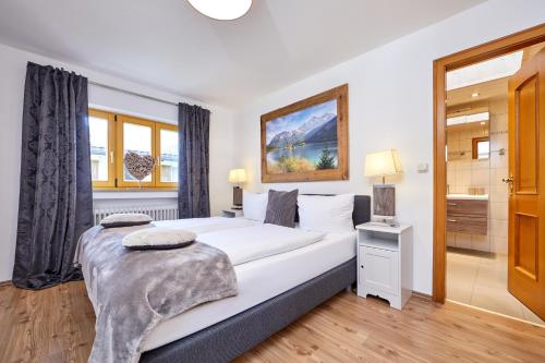 a bedroom with a large white bed and a bathroom at Ferienwohnung Anna in Garmisch-Partenkirchen