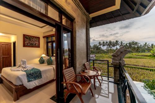 a bedroom with a bed and a balcony with a view at Juwuk Manis in Ubud