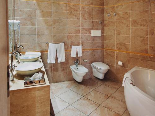 a bathroom with two toilets and a sink and a tub at Villa Zina Family Resort in Custonaci
