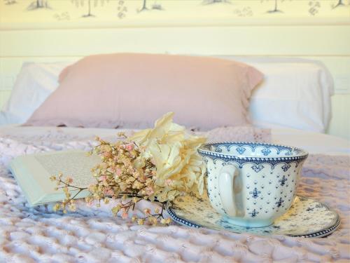 a blue and white cup and a plate with flowers on a bed at El Patio de los Jazmines Boutique-House in Consuegra