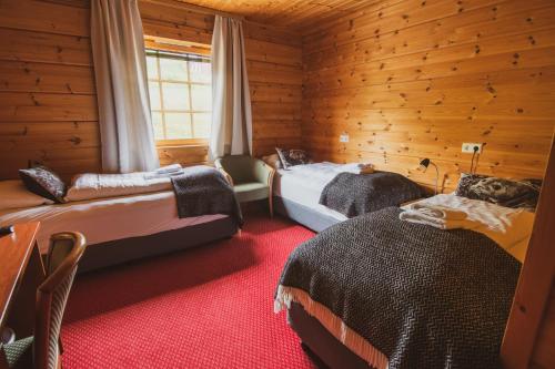 a bedroom with two beds in a wooden cabin at Hotel Framtid in Djúpivogur