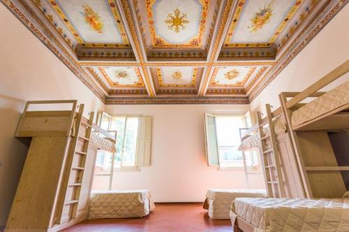 a room with three bunk beds and a ceiling at Student's Hostel Estense in Ferrara
