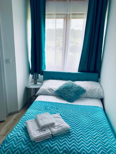 a bed with blue curtains and two towels on it at Parkowy Kudowa in Kudowa-Zdrój